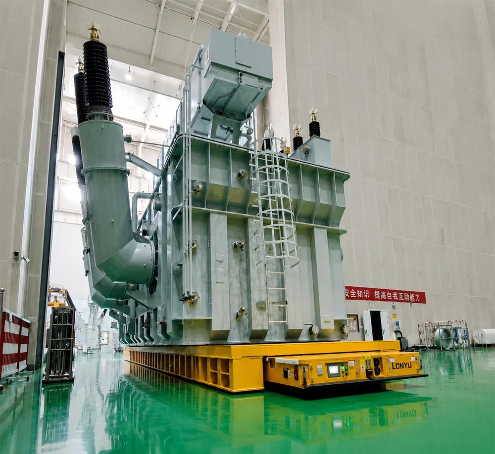 300-ton heavy-duty AGV transporting a UHV transformer inside a manufacturing plant with hydraulic suspension and omnidirectional steering system banner