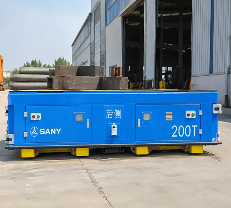 sany 200t trackless A blue SANY 200T heavy-duty trackless transfer cart carrying large metal components outside an industrial factory building.