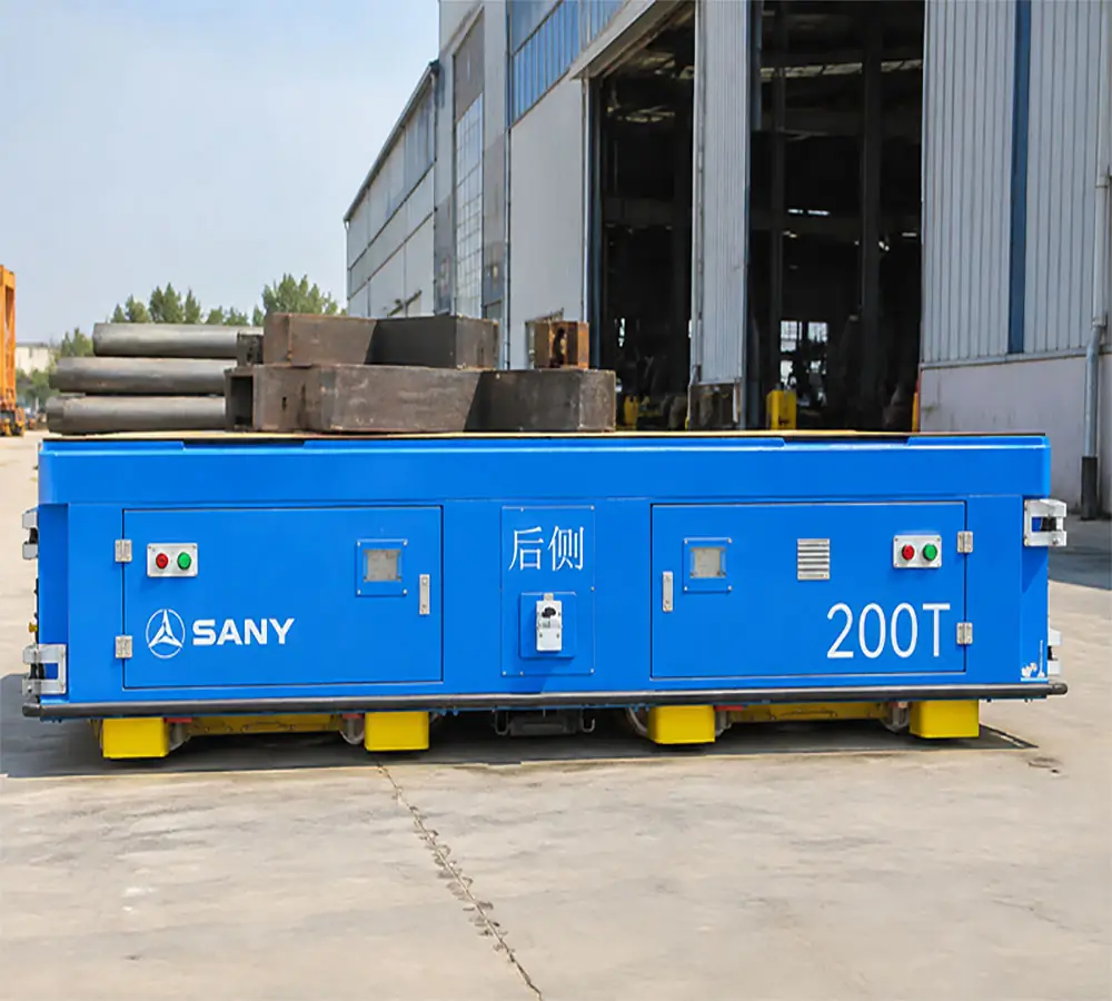 sany 200t trackless A blue SANY 200T heavy-duty trackless transfer cart carrying large metal components outside an industrial factory building.